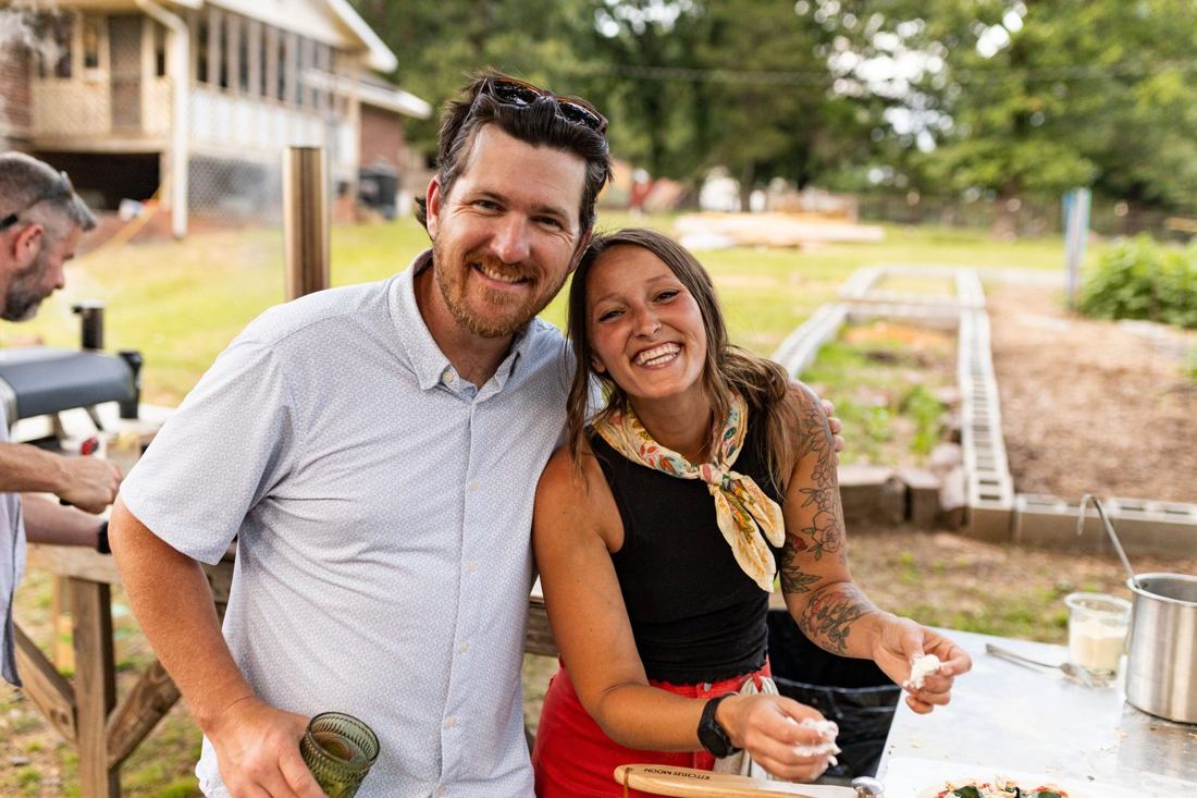 Jill and a smiling guest leaning in together at the pizza station