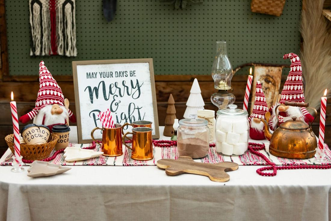 The hot cocoa table with gnomes, copper mugs, jars of cocoa and giant marshmallows, and a copper kettle